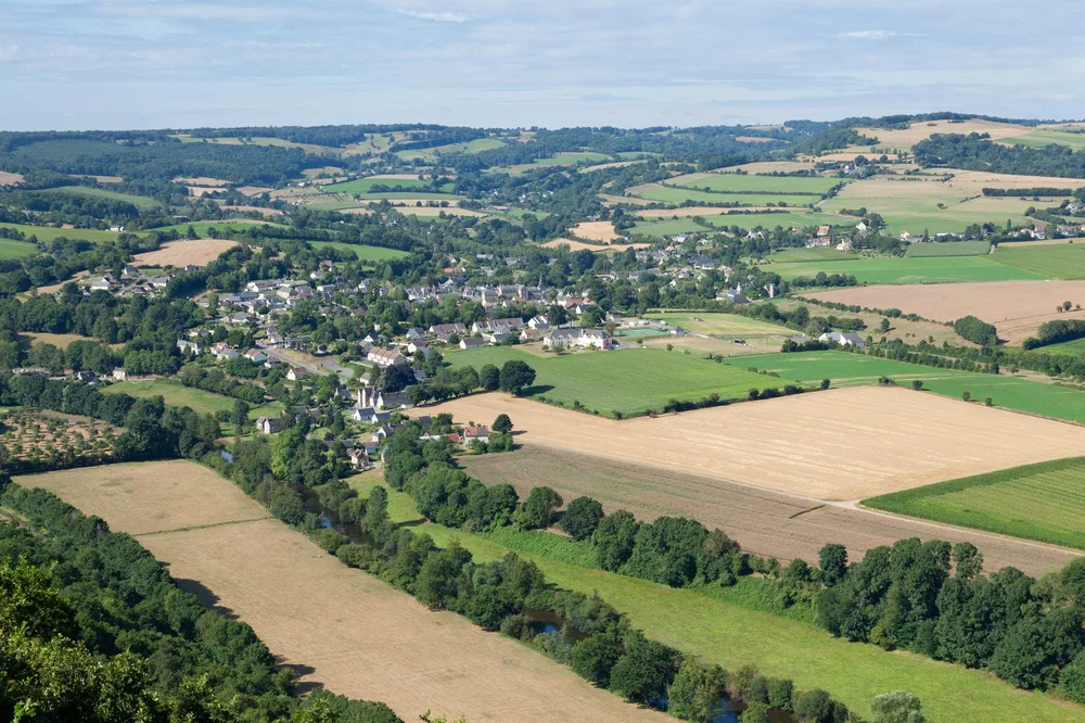 Vue aérienne du bocage breton, champs verts découpés par des haies, village dans la vallée, paysage de recherche immobilière rurale en Finistère