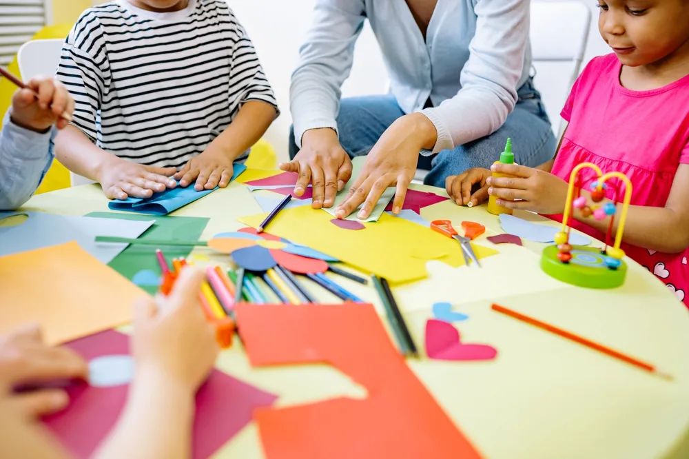 Enfants travaillant en petits groupes sur une activité créative en classe, lumière naturelle et atmosphère studieuse
