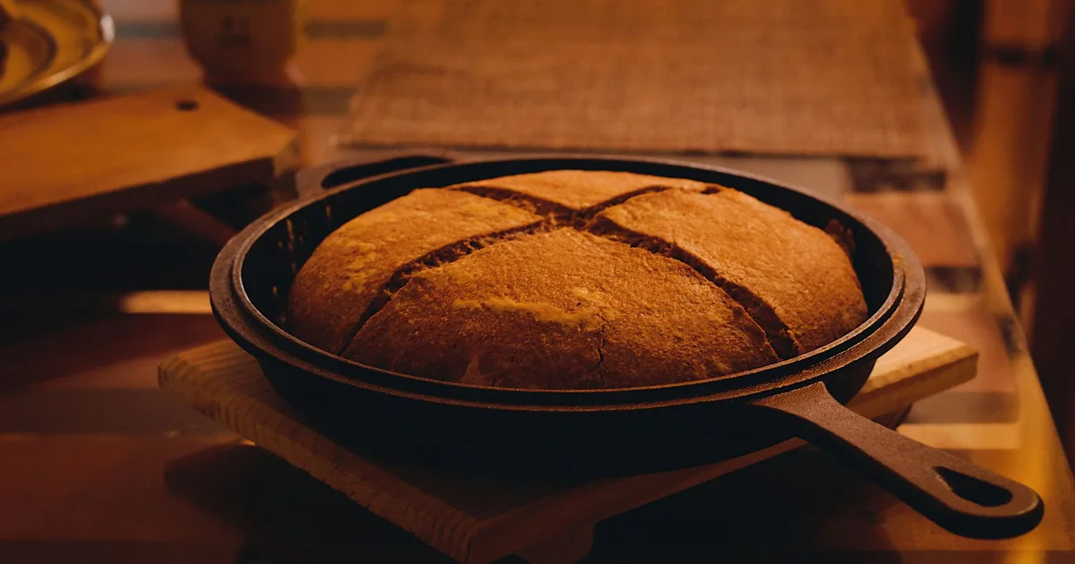 Pain artisanal cuit dans une cocotte en fonte posée sur une table en bois rustique, ambiance cuisine de campagne bretonne