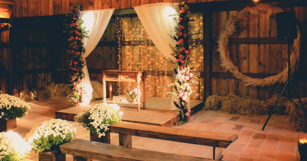 Intérieur d'une grange en bois aménagée avec guirlandes lumineuses pour une cérémonie