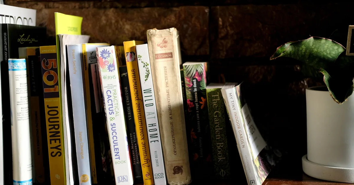 Livres de jardinage biologique sur une étagère en bois avec mur en briques, lumière naturelle, ambiance atelier de jardinier