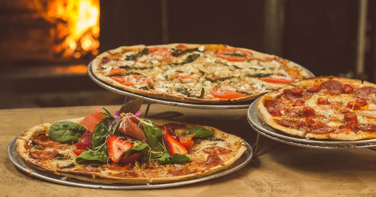 Pizzas maison sortant du four à bois, garnies de légumes du potager